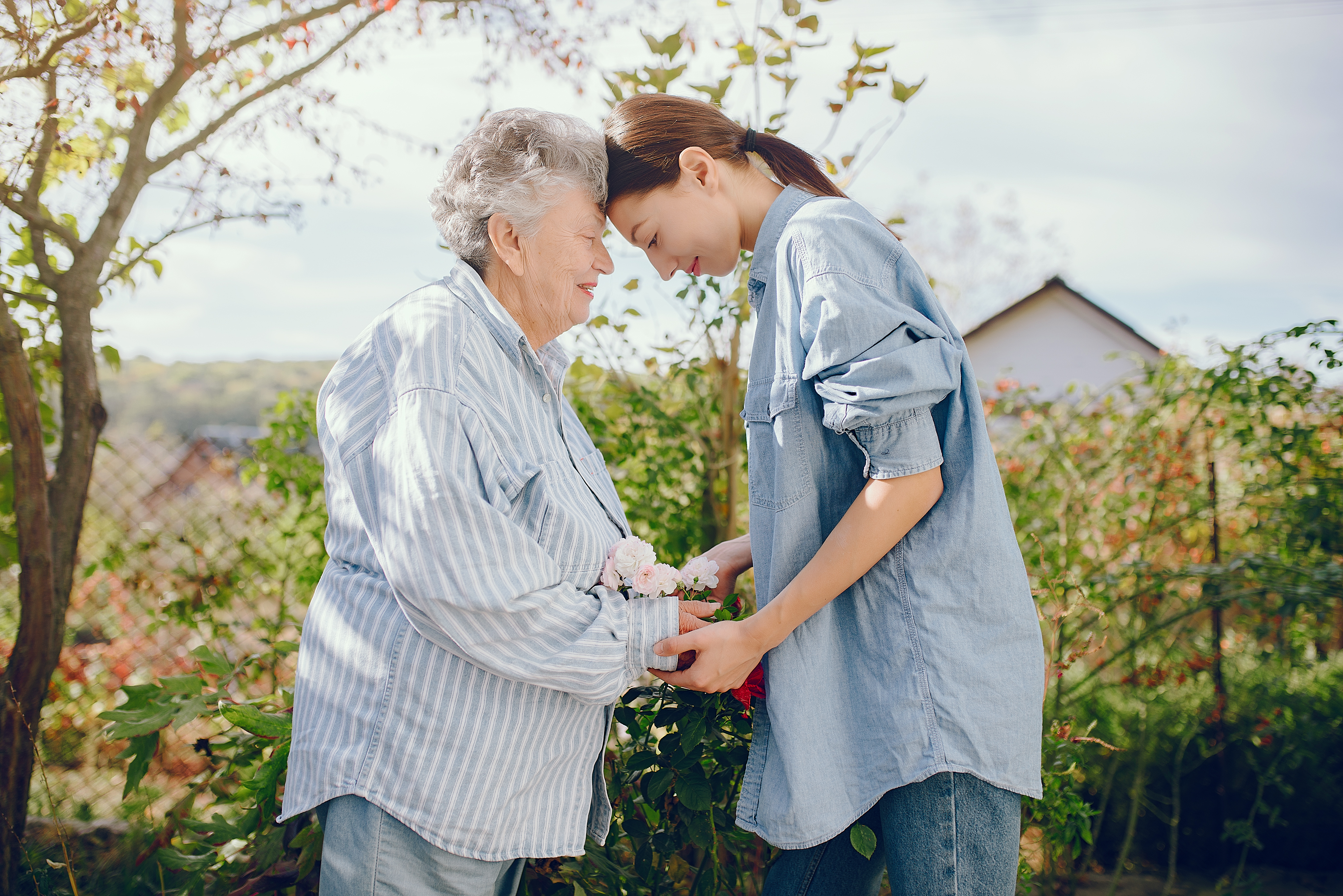 Old woman holding a flowers. Woman in a blue shirt. Grandmother with granddaughter.